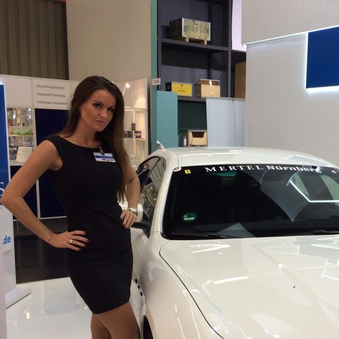 Modelhostess präsentiert ein Auto auf einem Messestand