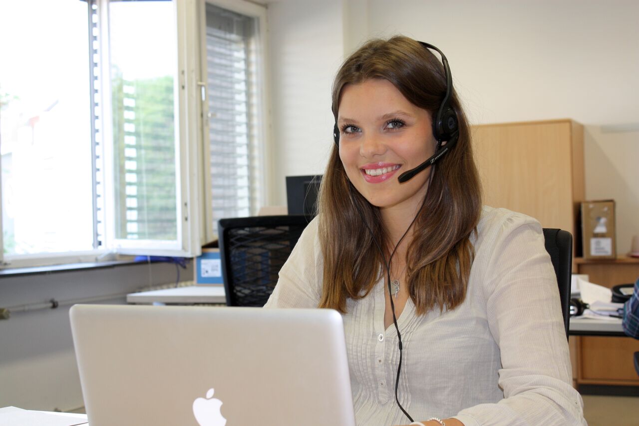 Mitarbeiterin mit Headset arbeitet am Laptop im Büro – Telefonakquise Schulung