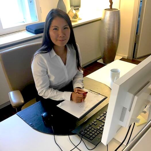 Büroaushilfe sitzt an einem Schreibtisch mit Computer und Notizblock in einem modern eingerichteten Büro